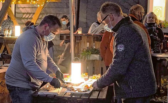 Hotelier Andreas Benkendorf (r.) bediente sich beim Flammlachs am Know-how der Fisch-Spezialisten aus Wingeshausen – im Foto Martin Haschke –, die in diesem Jahr ohne Weihnachts-Zeitreise auskommen müssen. (SZ-Foto: Guido Schneider)