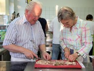 Kochkurs Niederlande (VHS) von Hans-Christian Radenbach: Kursteilnehmer schneiden hochkonzentriert das gekochte Hühnchen; Foto: Björn Weyand (SZ)