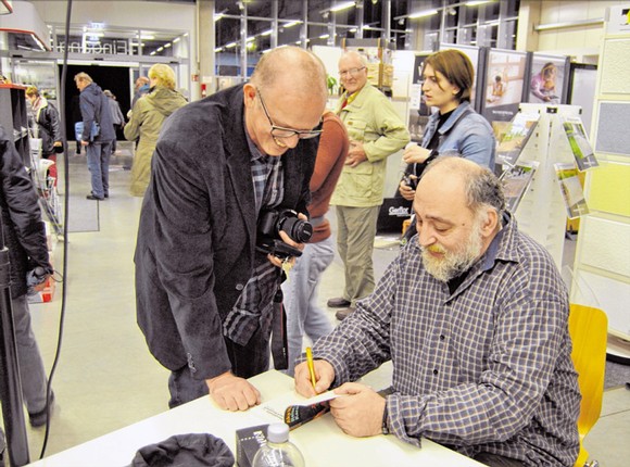 Während der anschließenden Signierstunde im Rompel Baumarkt können die Besucher dem Schriftsteller Aka Morchiladze (rechts) Fragen stellen oder Gespräche führen. (WP-Foto: Carolin Battenfeld)