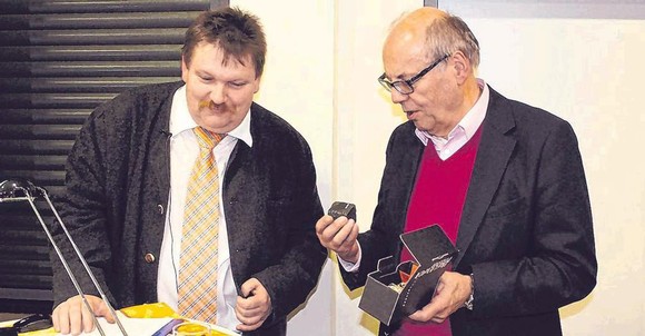 Dr. Ulf Lückel dürfte sich was dabei gedacht haben, die orangene Krawatte aus dem Schrank genommen zu haben. Otto Marburger (r.), Ehrenvorsitzender der Kulturgemeinde, überreichte dem Referenten als Dank den Pflasterstein. (SZ-Foto: Holger Weber)