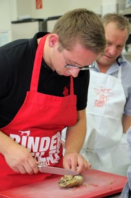 Kochkurs Niederlande (VHS) von Hans-Christian Radenbach: Kursteilnehmer schneidet hochkonzentriert das gekochte Hühnchen; Foto: Björn Weyand (SZ)
