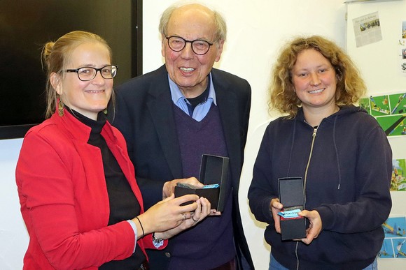 Bildungsreferentin Hannah Wolf (l.) vom Philippinenbüro und Lea Burwitz, Projektmanagerin für Kommunale Entwicklungspolitik, erhielten von Otto Marburger aus dem Organisations-Team die beliebten Literaturpflastersteine. (Foto: Jens Gesper)