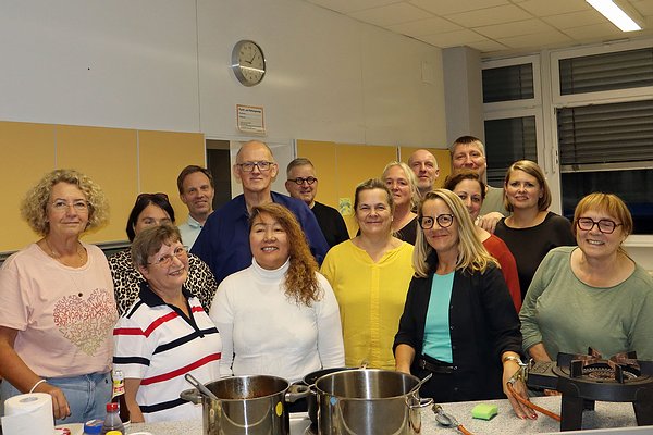 Nach der Adobo-Abend-Premiere stellten sich alle Anwesenden des ersten VHS-Kochkurses „Philippinen“ auf dem Literaturpflaster 2025 zum Gruppenbild in der Lehrküche der Realschule auf dem Berleburger Stöppel auf.