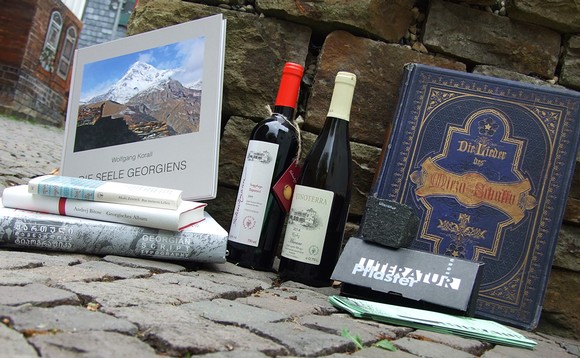 Die Bücher und den georgischen Wein auf dem Foto gibt es im Antiquariat Armin Nassauer, die Flyer liegen an vielen Kulturinstitutionen der Städte und Gemeinden aus, den Pflasterstein gibt es als Präsent für teilnehmende Künstler – und spannende Literatur vom 14. September bis 9. November in Bad Berleburg. (Foto: Olaf neopan Schwanke)